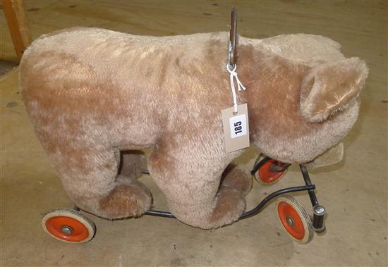Early 20th century plush bear on wheeled metal frame, with amber glass eyes and carry/pull handle